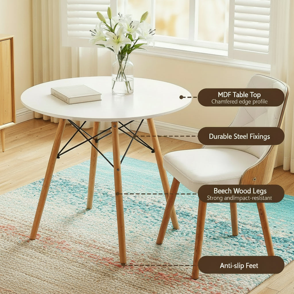 Round dining table with white MDF top and wooden legs in a room with a window and curtains.