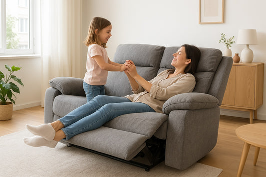 Woman and child sitting on a gray recliner in a bright living room.