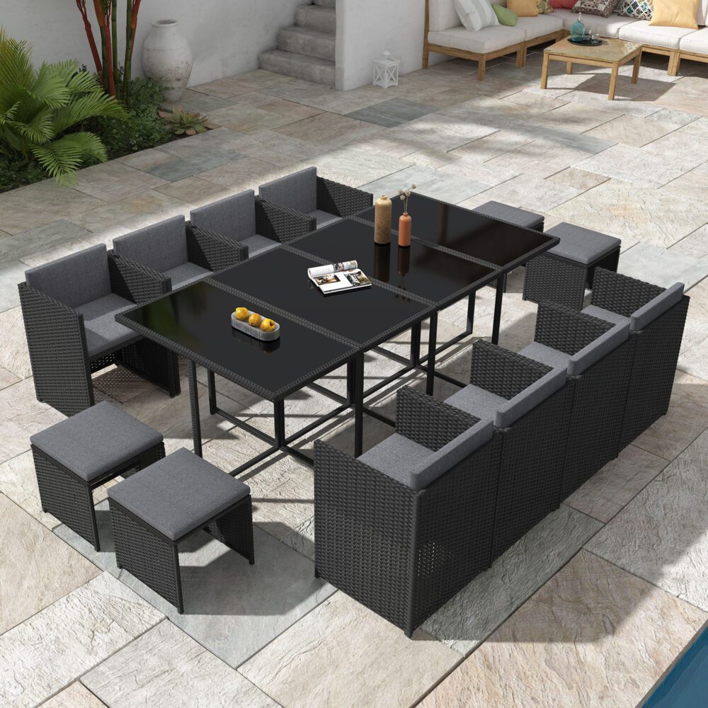 Outdoor patio furniture set with black tables and gray cushions on a stone patio.