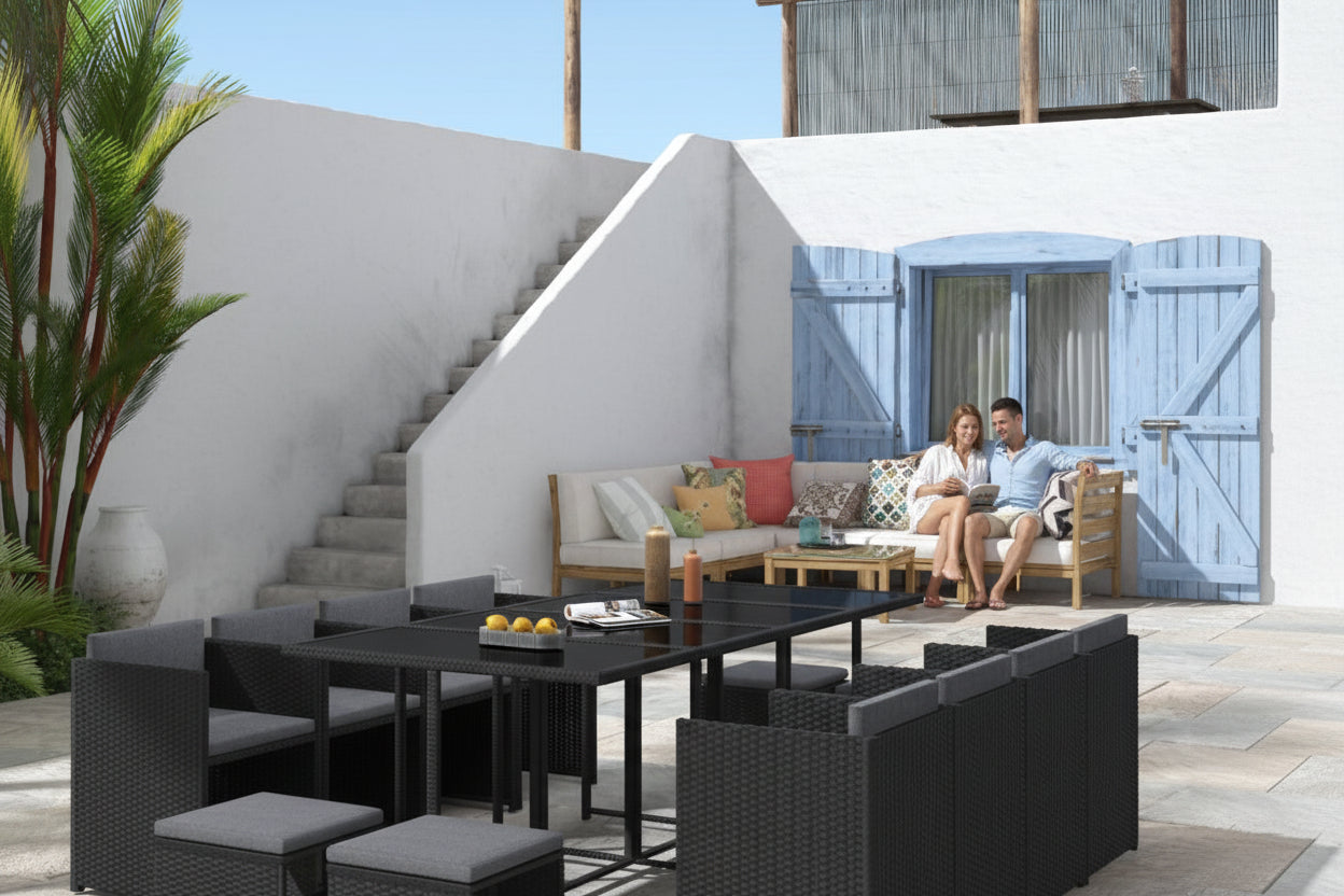 Outdoor patio furniture set with black wicker chairs and table on a stone patio.