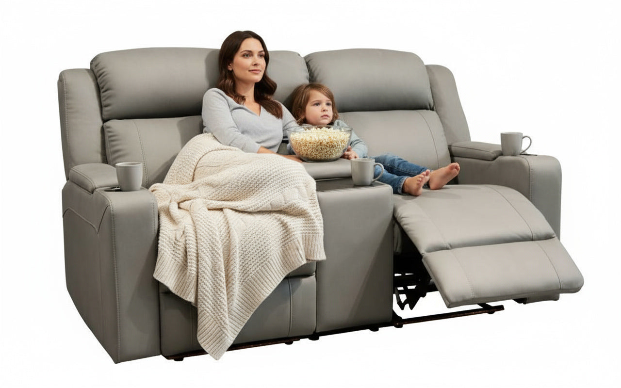Woman and child sitting on a gray recliner with popcorn, blanket, and cups.