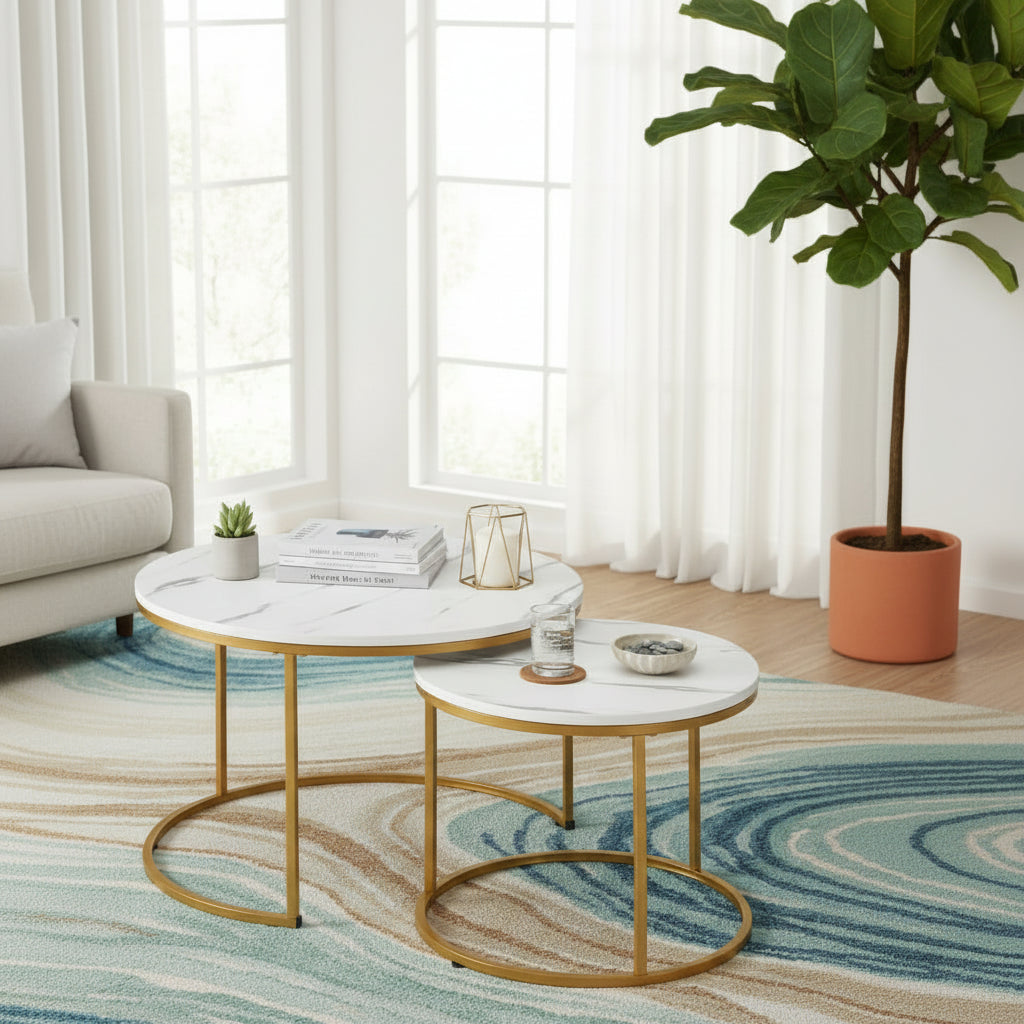 Two round nesting side tables with white marble-patterned tops and gold metal frames, styled with books, a reed diffuser, a cup of coffee, and a vase of dried grass.