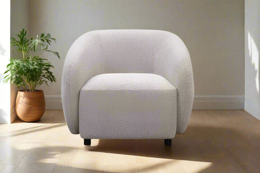 White textured armchair in a room with a plant and wooden floor.